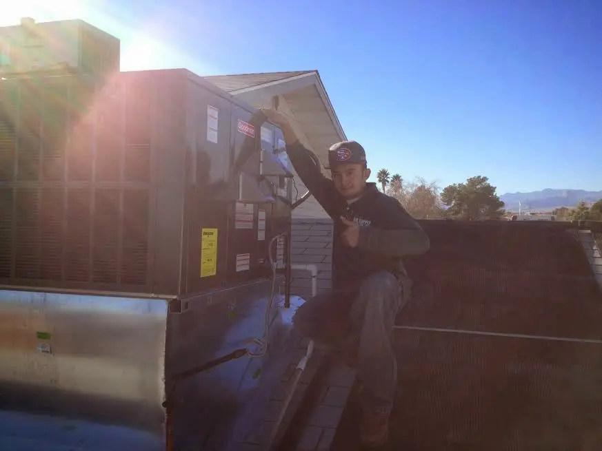 HVAC technician performing AC Tune-Up on a rooftop unit in South Weber